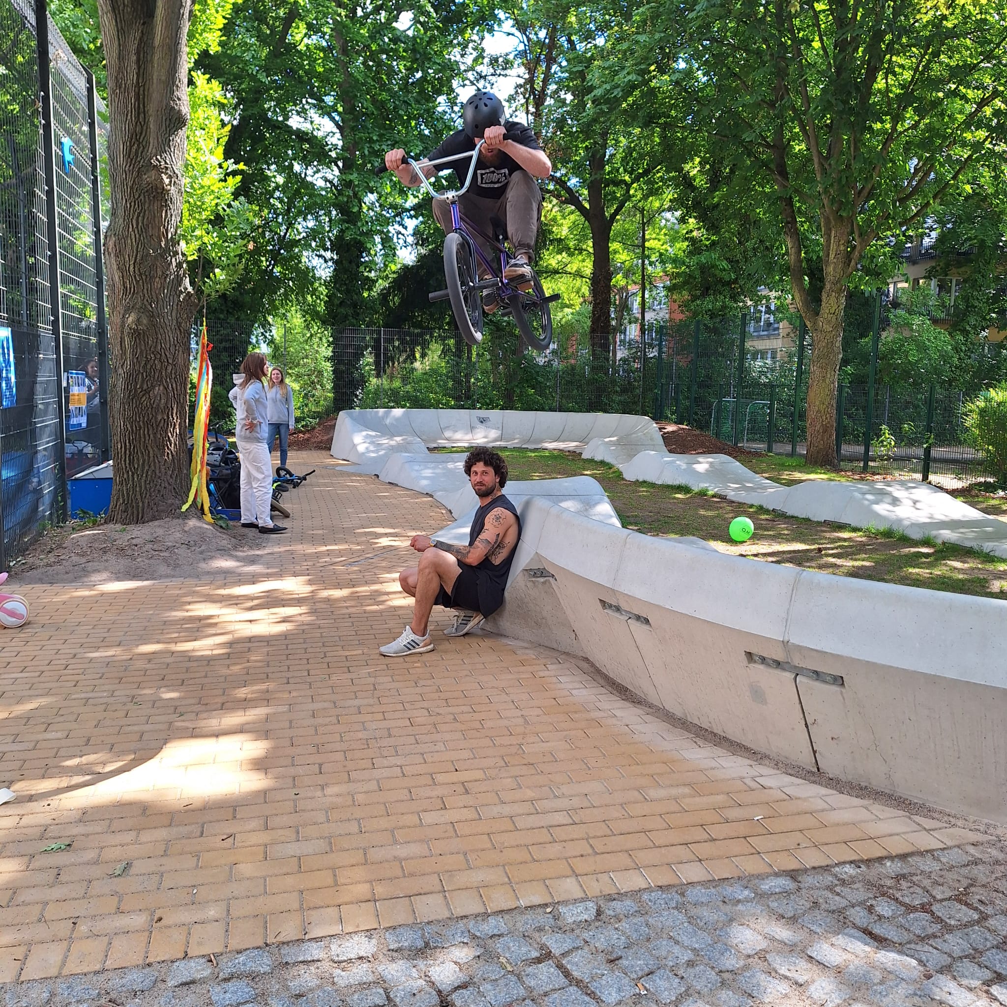 BMX-pyöräiljä hyppää pumptrackilta ihmisen yli.